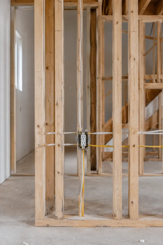 New cable running through drilled studs in an open wall during a renovation.